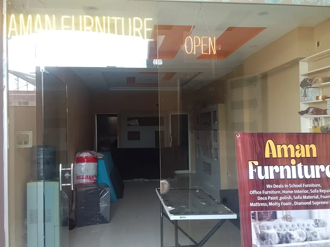 The Aman Furniture shop front with its lit sign and banner